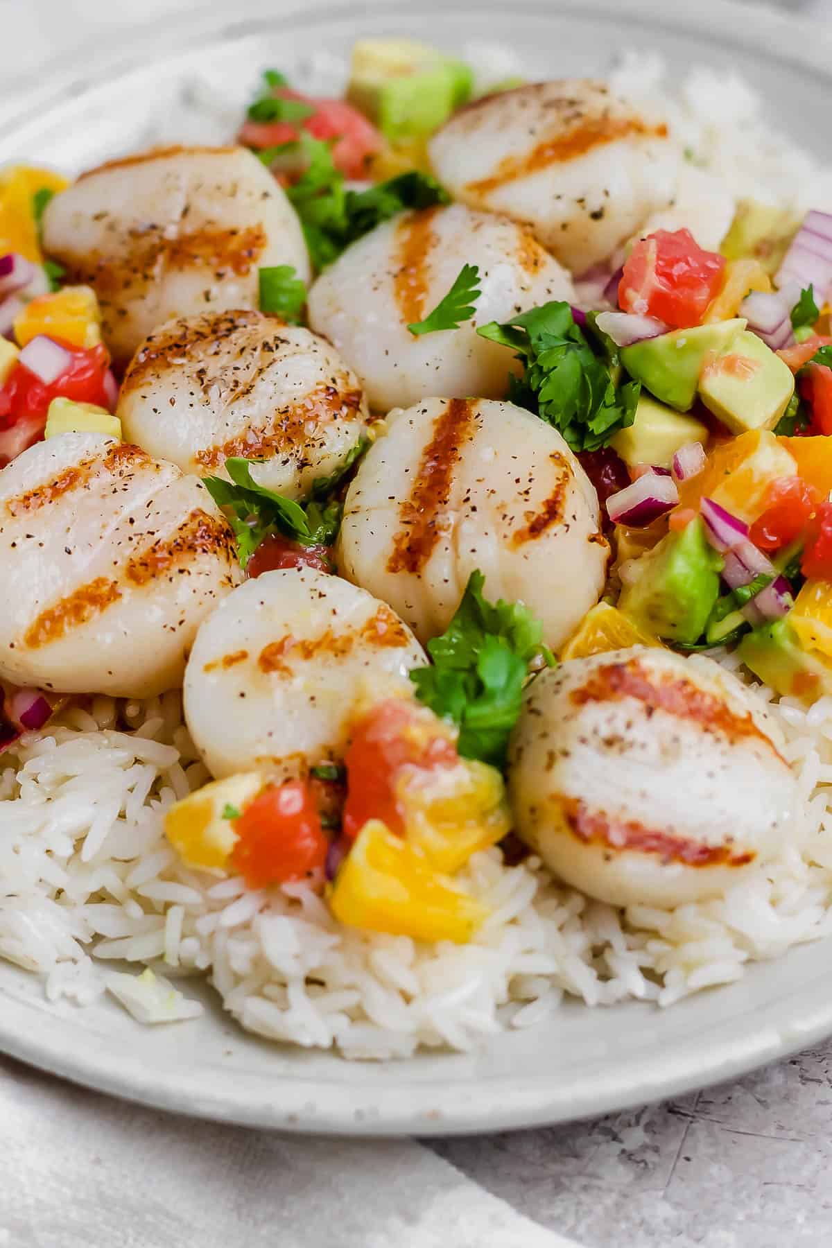 A full plate of grilled scallops, citrus salsa, and rice.