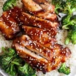 A plate of rice topped with grilled broccoli and grilled teriyaki chicken with sesame seeds on top.