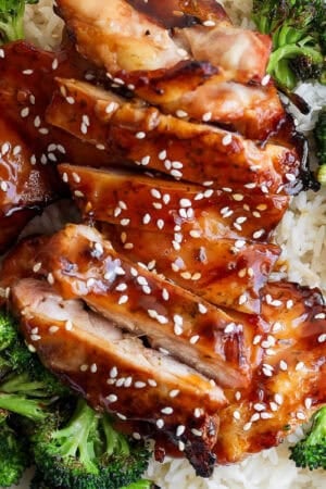 A plate of rice topped with grilled broccoli and grilled teriyaki chicken with sesame seeds on top.
