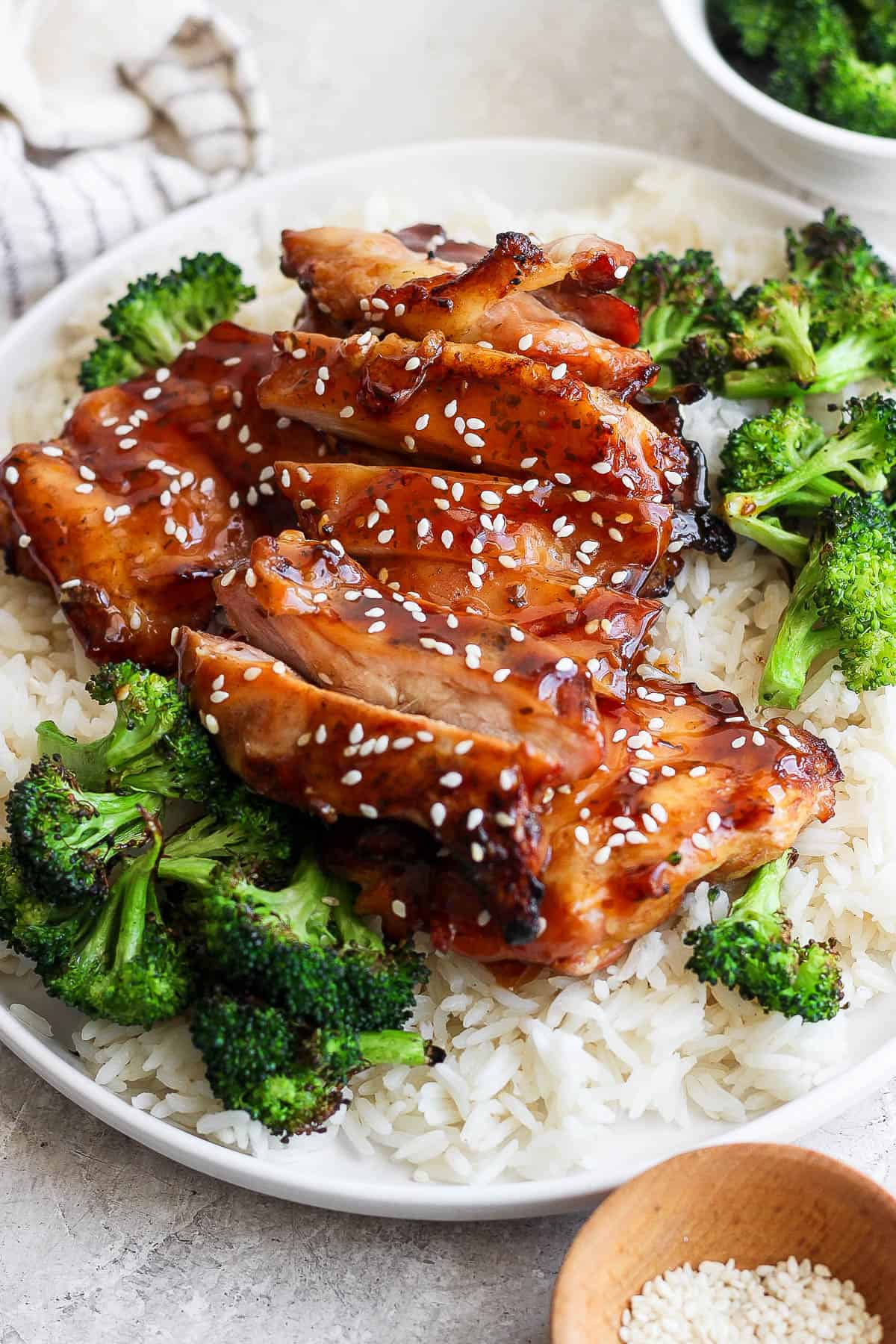 Grilled teriyaki chicken thighs on a plate with white rice and grilled broccoli.