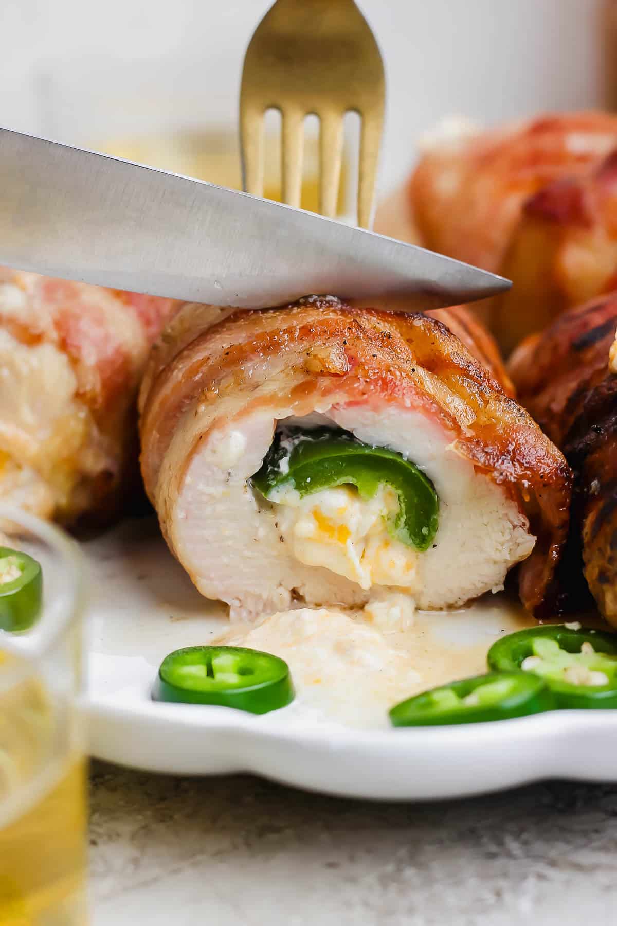 A bacon wrapped jalapeno chicken breast being cut in half.