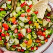 Close up of a big bowl of pickle de gallo with a corn chip sticking out.