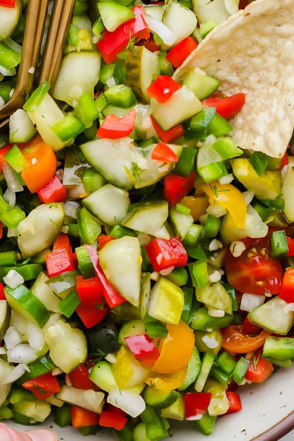 Close up of a big bowl of pickle de gallo with a corn chip sticking out.