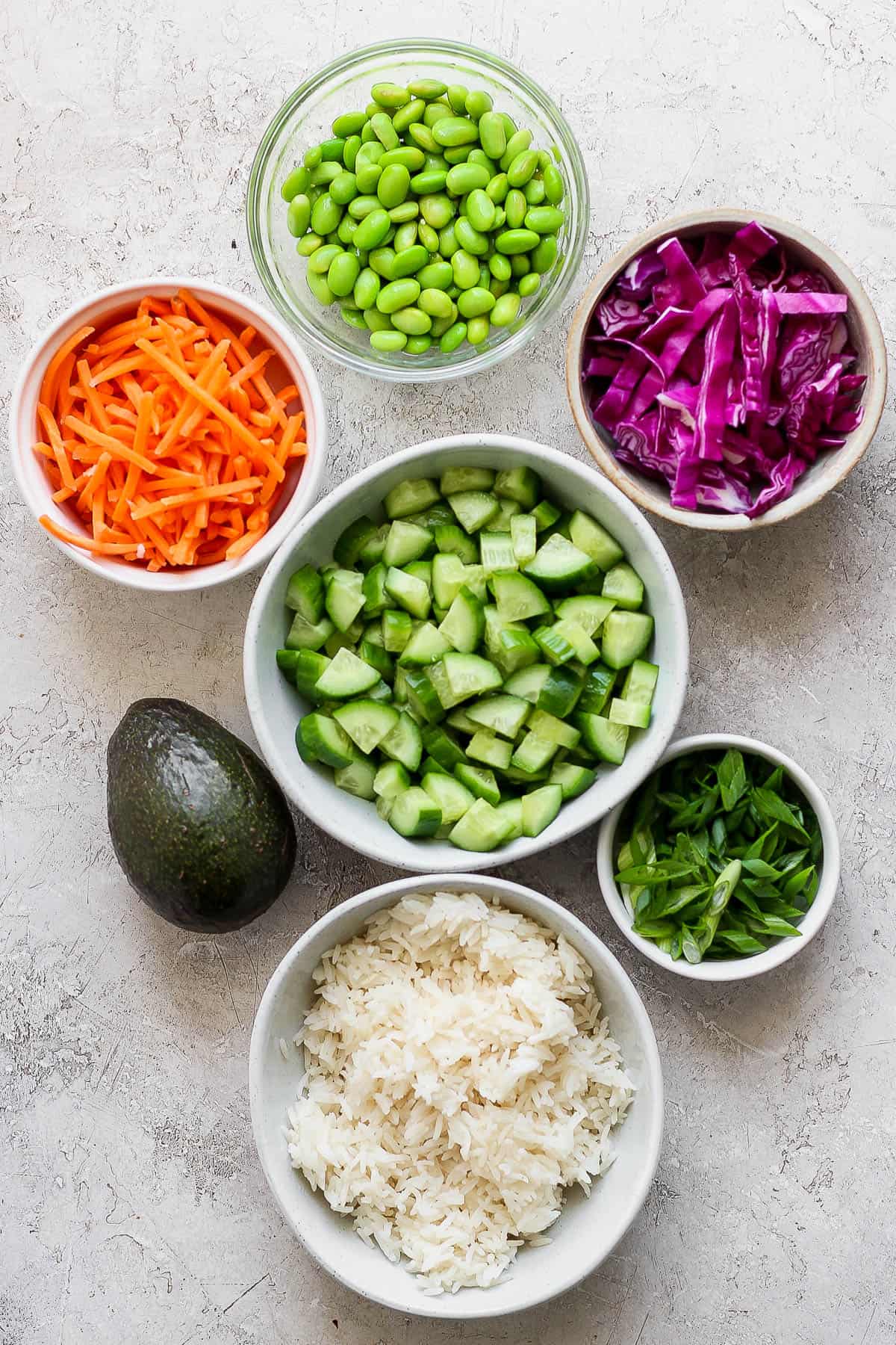 Teriyaki Chicken Bowls - simple and delicious weeknight dinner (or meal prep!) that your whole family will love! (Whole30, Paleo, GF + DF) #teriyakichickenbowls #teriyakichickenbowl #whole30dinner #instantpotmeals #paleodinner #healthychickendinner Individual bowls of rice, quartered and chopped cucumber, green onion, shredded carrots, purple cabbage, and whole avocado.
