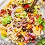 A bowl of bacon ranch pasta salad with two spoons sticking out.