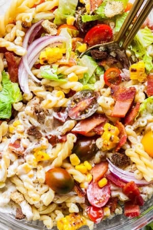 A bowl of bacon ranch pasta salad with two spoons sticking out.
