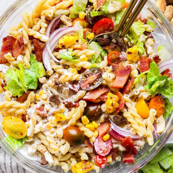 A bowl of bacon ranch pasta salad with two spoons sticking out.