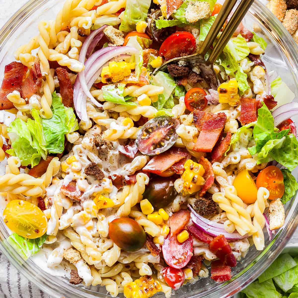 A bowl of bacon ranch pasta salad with two spoons sticking out.