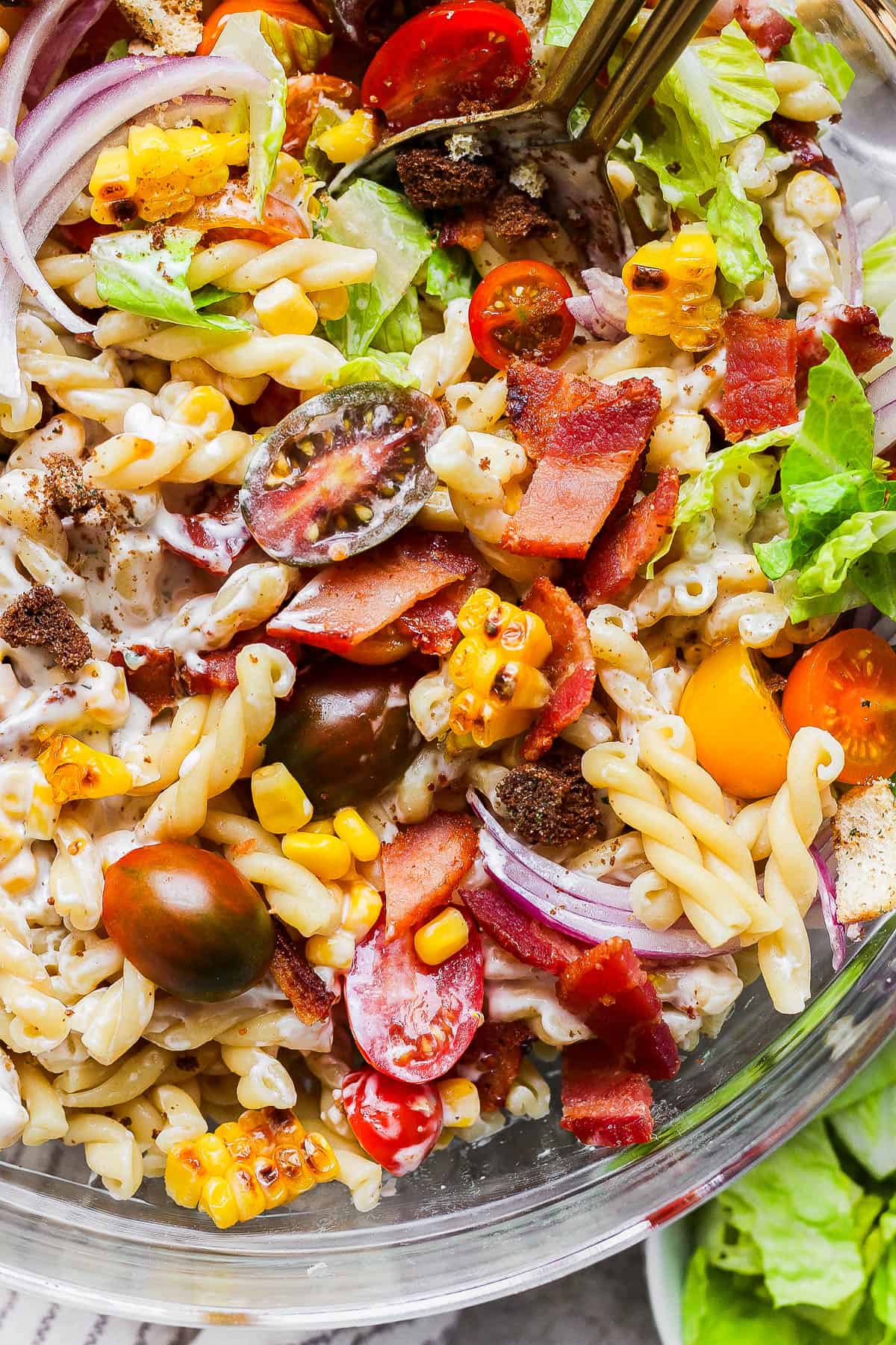 A fully mixed pasta salad in a glass bowl.