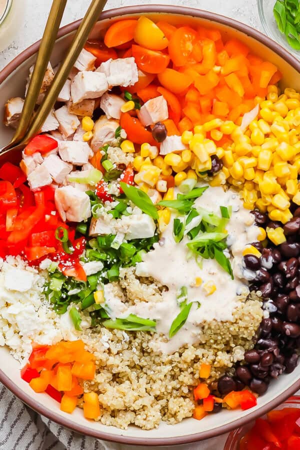 A big bowl of southwest quinoa salad with black beans, corn, bell peppers, feta cheese and a creamy southwest dressing on top.