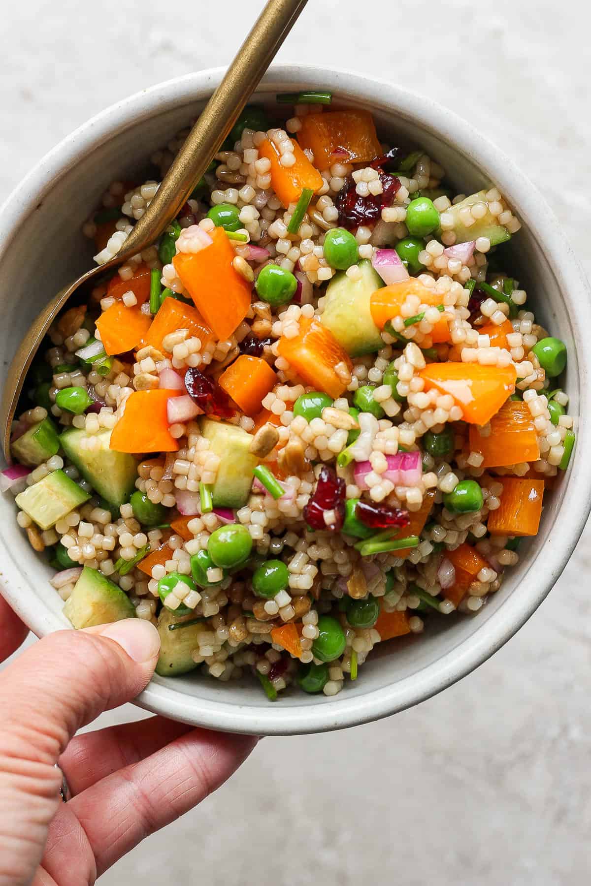 Acini di pepe salad in a bowl with a spoon.