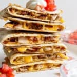A stack of chicken bacon ranch quesadillas with pico de gallo and sour cream.