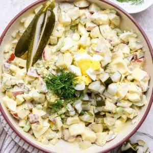 A big bowl of dill pickle potato salad with fresh chopped dill on top.
