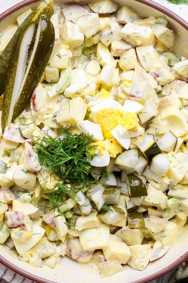 A big bowl of dill pickle potato salad with fresh chopped dill on top.