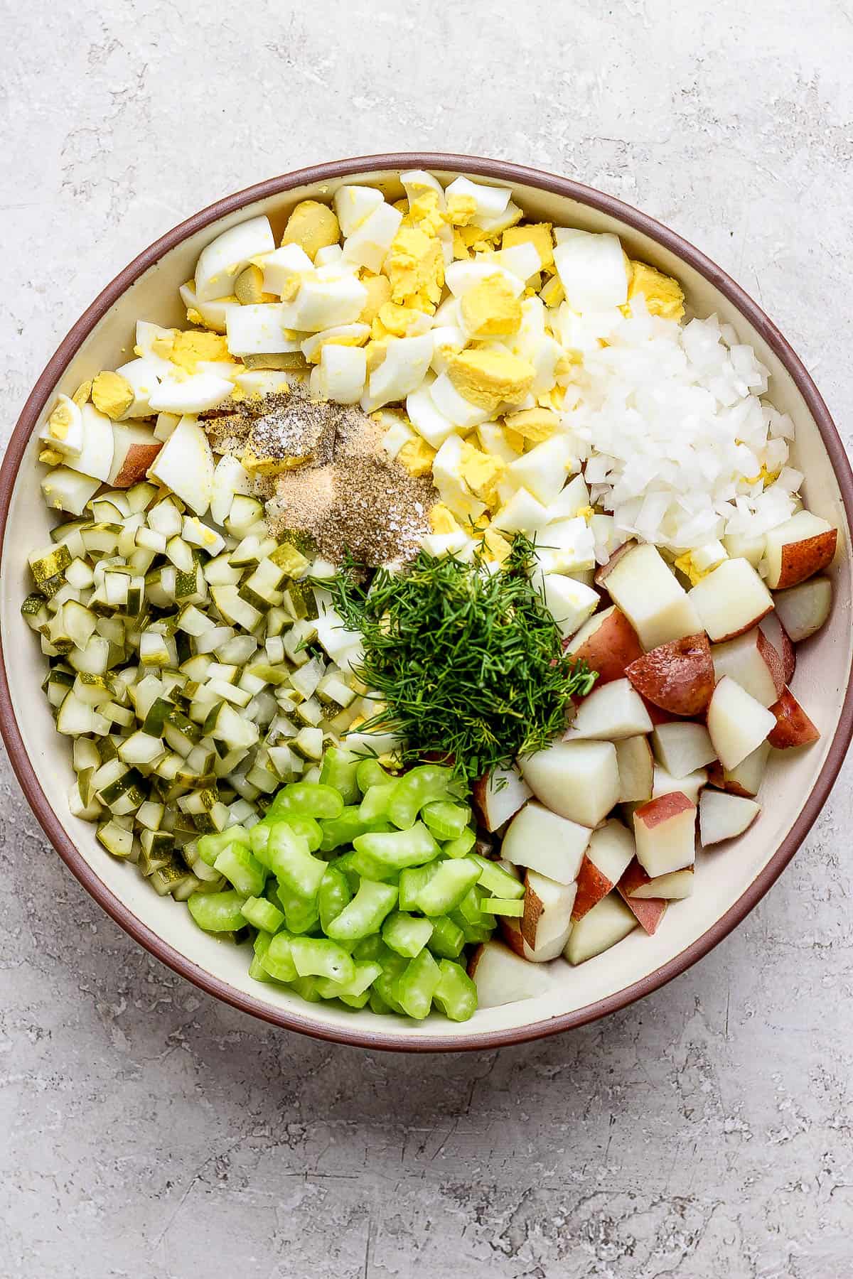 All of the dill pickle potato salad ingredients in a bowl, unmixed.
