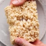 Someone holding an extra gooey rice krispie treat and pulling it apart.