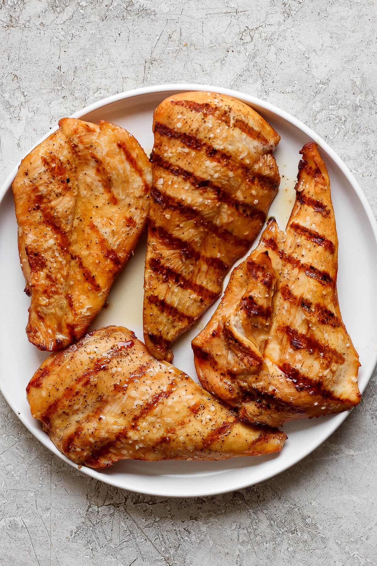 Grilled chicken cutlets on a white plate.