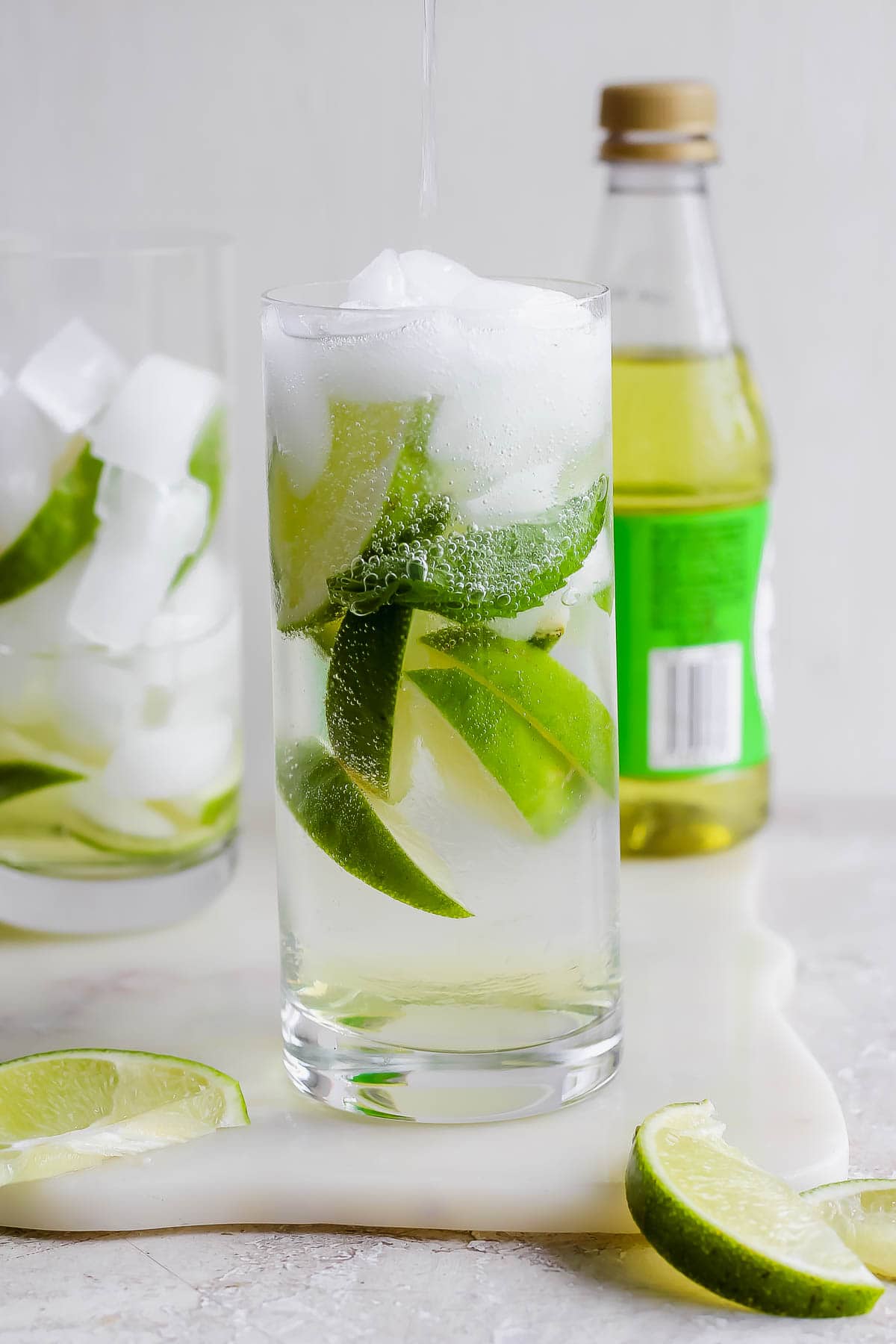 A Rose's gin and tonic in a glass with ice and lime wedges.