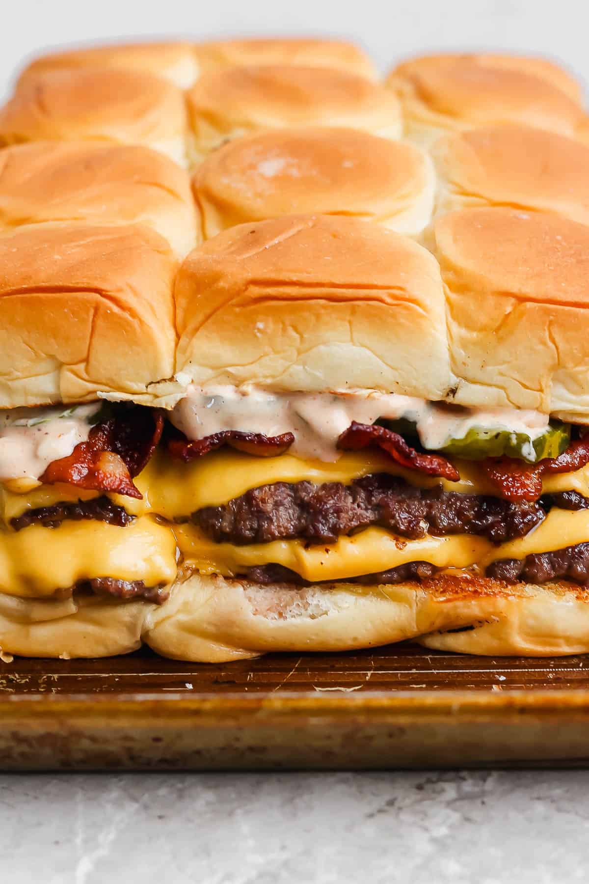 Smash burger sliders on a baking sheet.