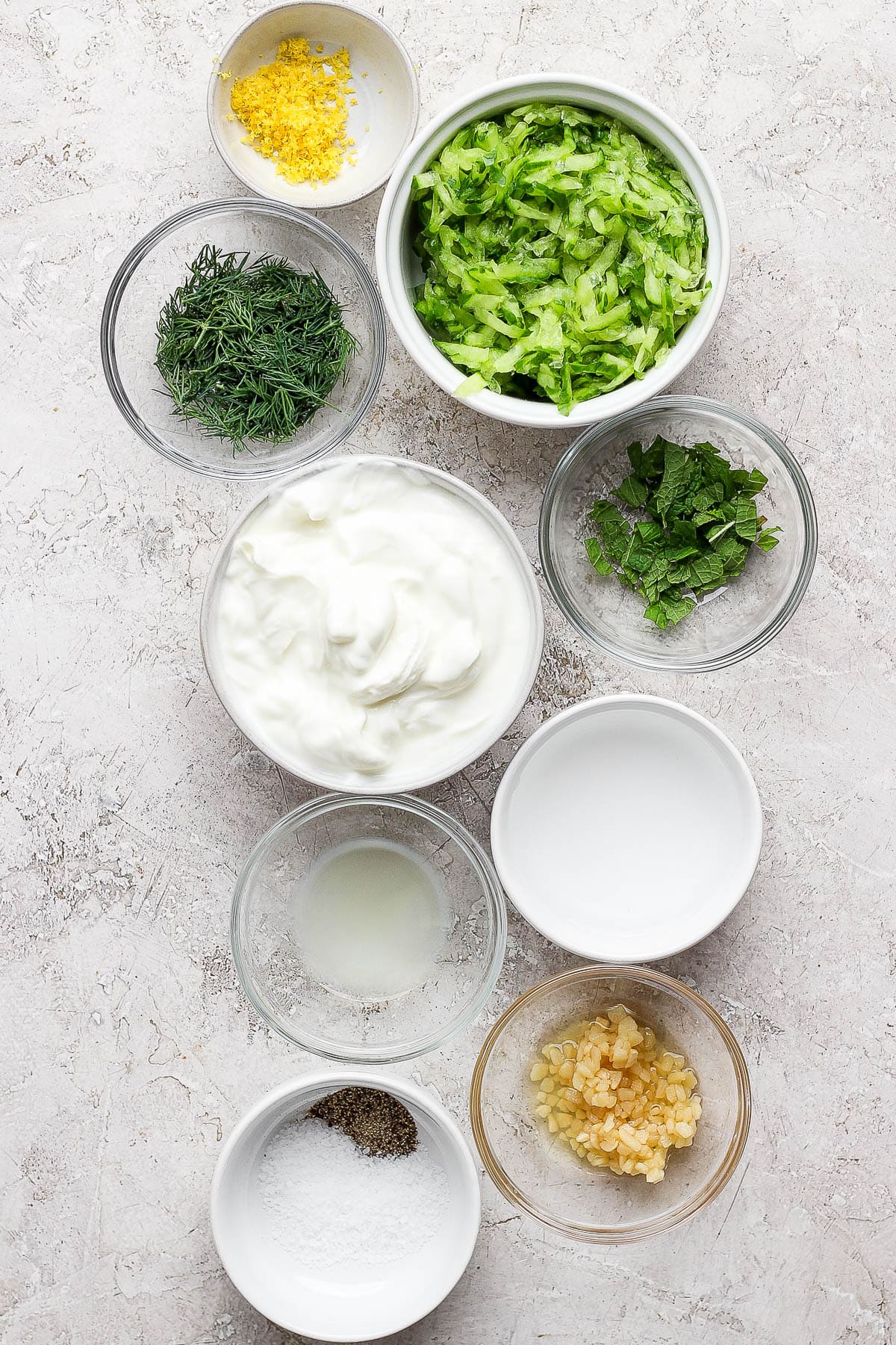 Tzatziki salad dressing ingredients in separate bowls.