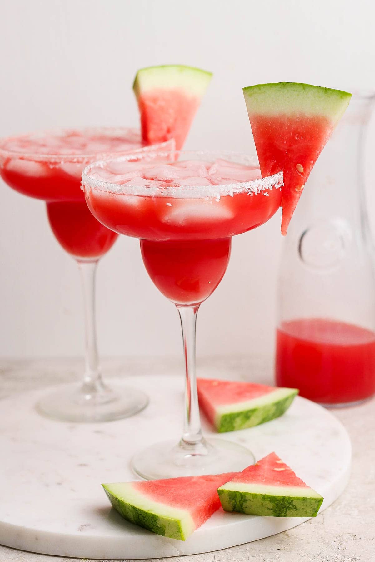 Two glasses of watermelon margaritas on ice.