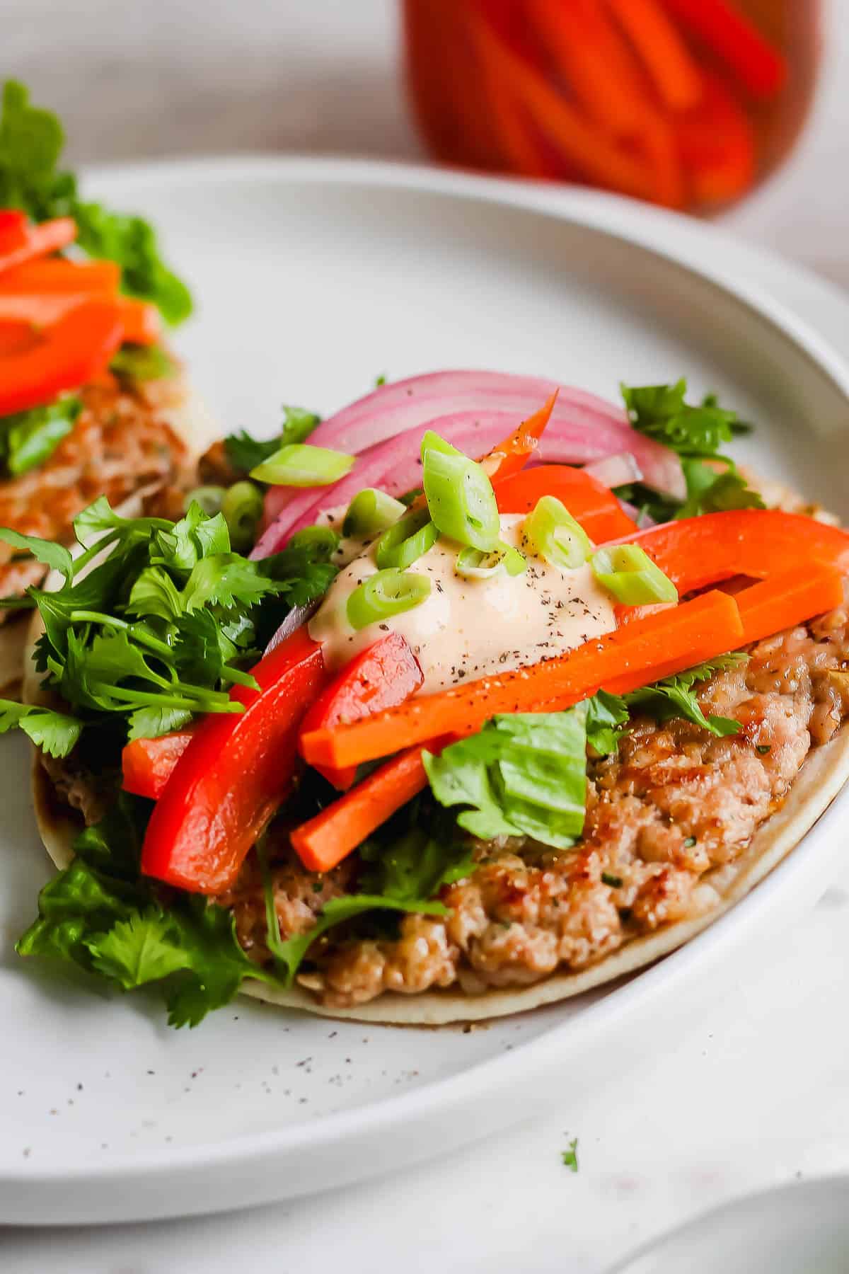 A fully assembled smash burger taco on a white plate.