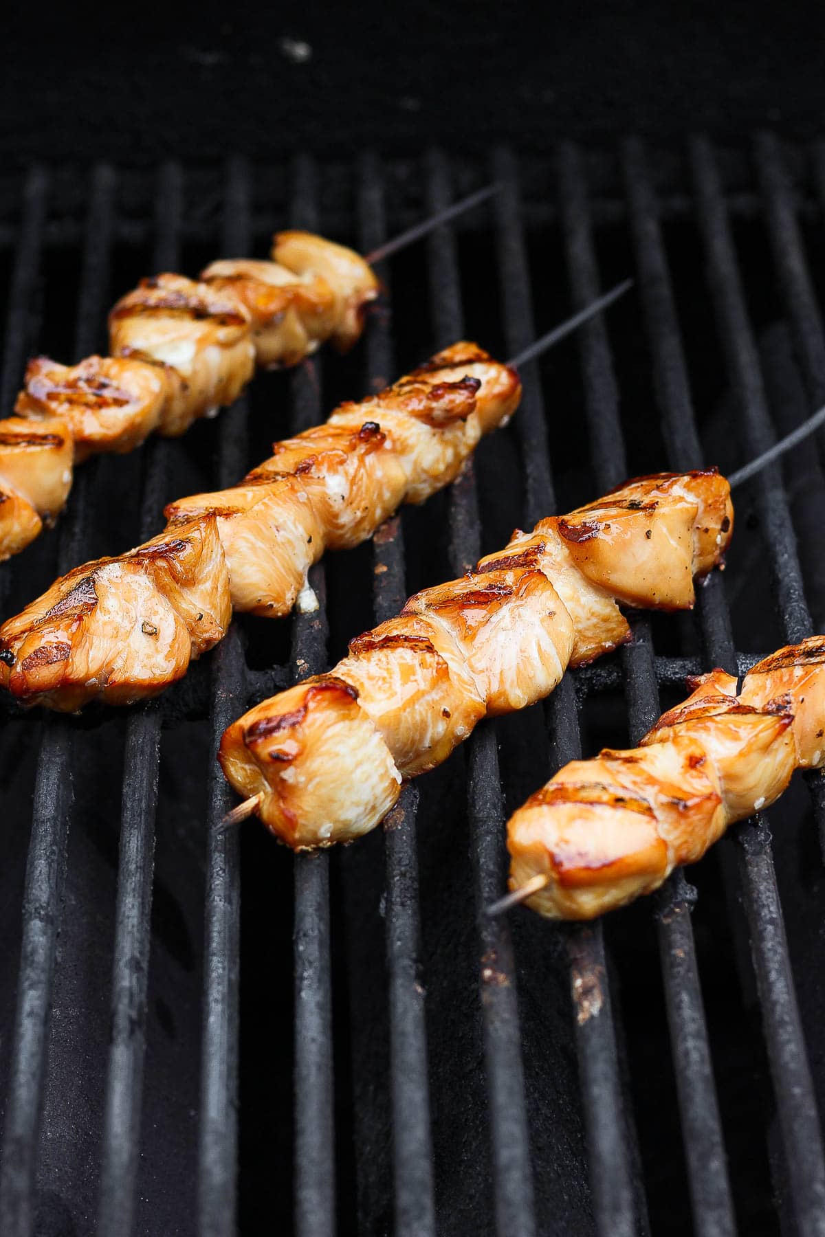 Four chicken skewers on the grill.