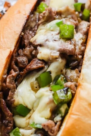 A cheesy blackstone philly cheesesteak in a bun with green peppers.
