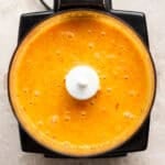 A top down shot of a small food processor filled with homemade carrot ginger salad dressing.