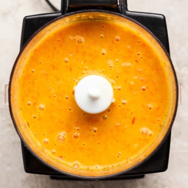 A top down shot of a small food processor filled with homemade carrot ginger salad dressing.