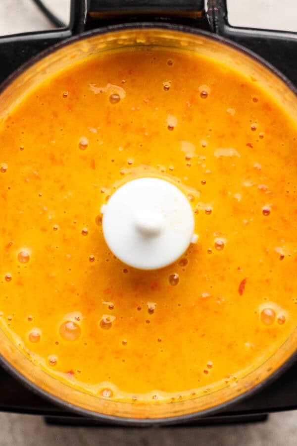 A top down shot of a small food processor filled with homemade carrot ginger salad dressing.