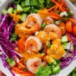 A bowl of Japanese ginger salad with shrimp in a bowl with carrot ginger dressing on top.