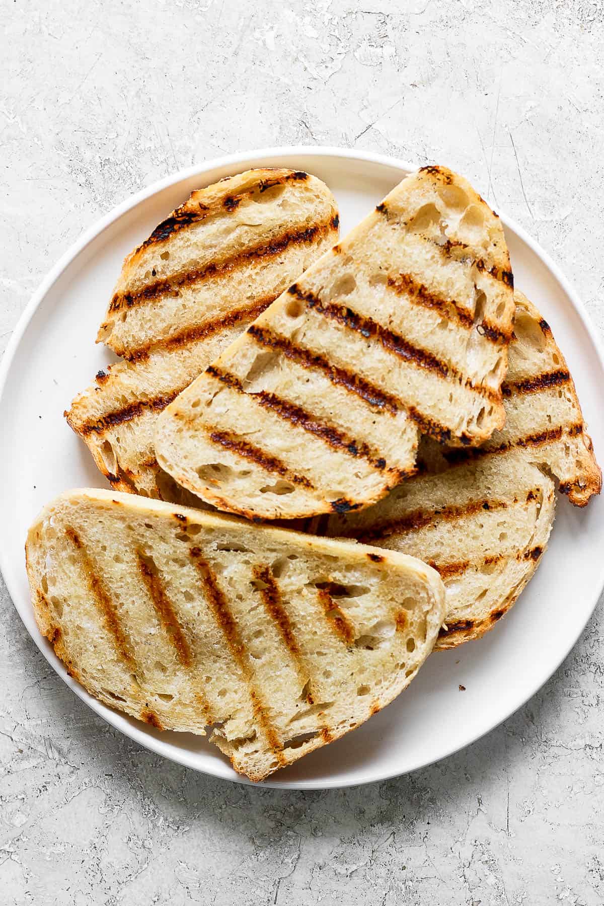 Slices of grilled bread on a white plate.