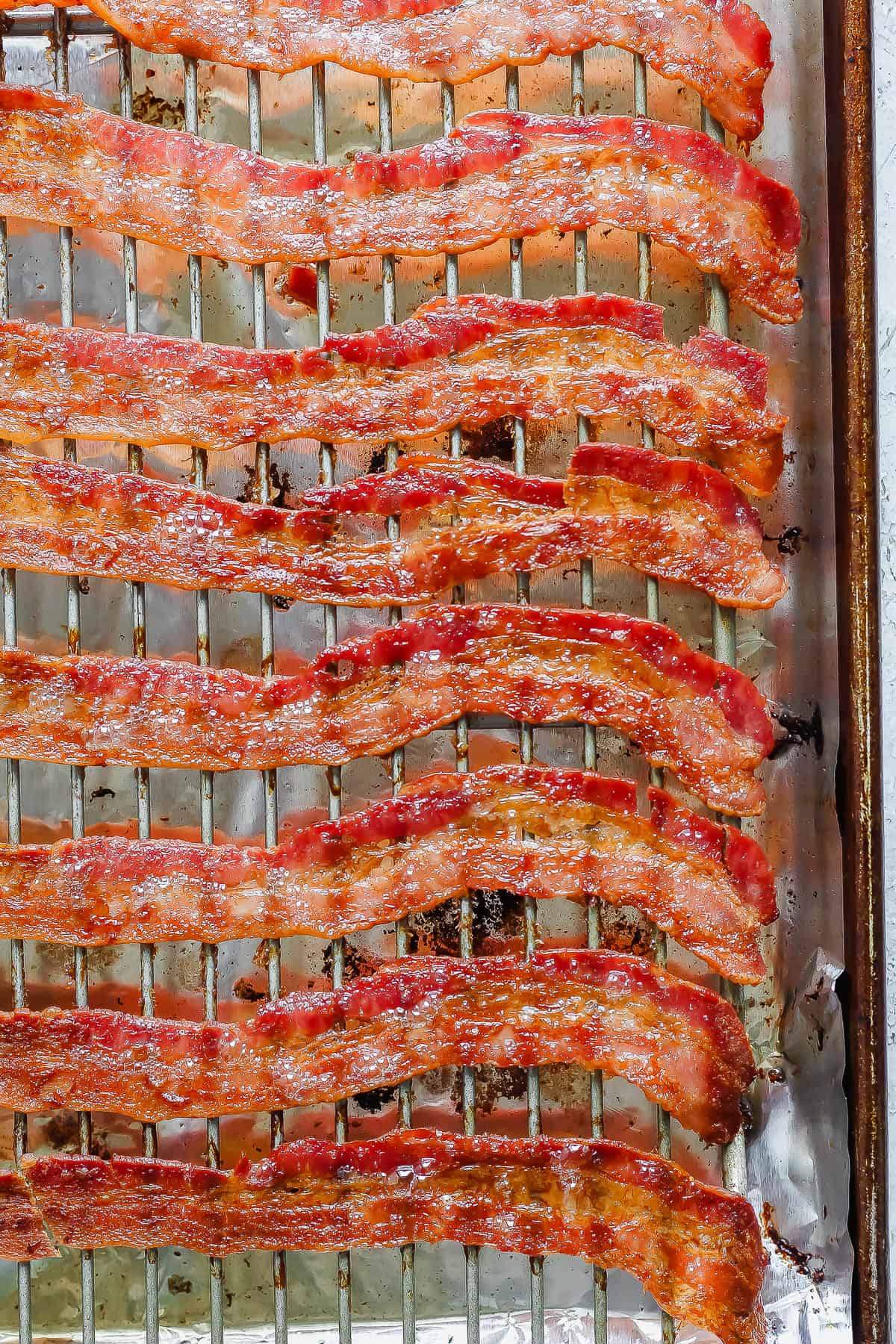 Cooked bacon on a rimmed baking sheet lined with foil with a wire rack on top.