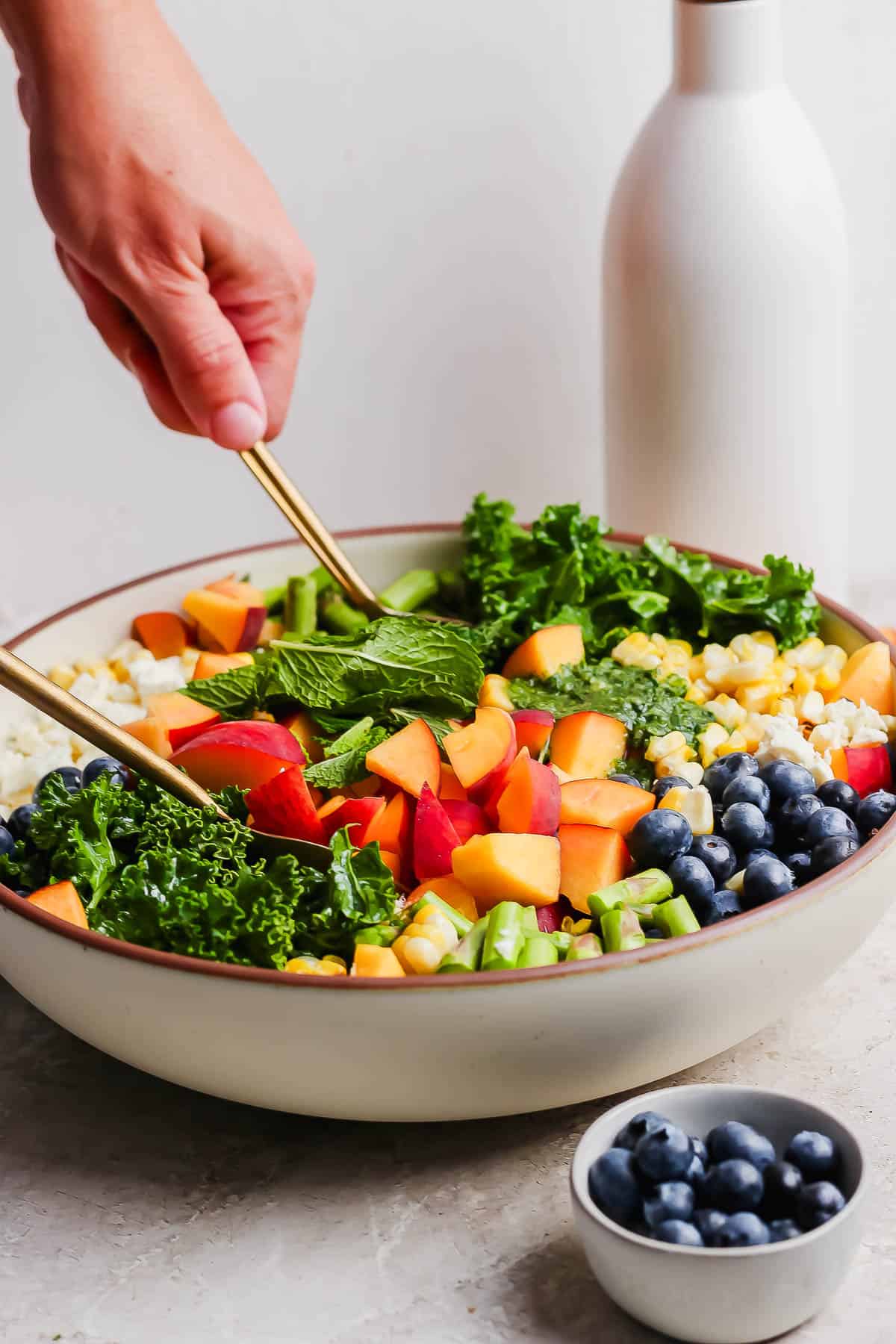 The kale salad being tossed with two spoons.