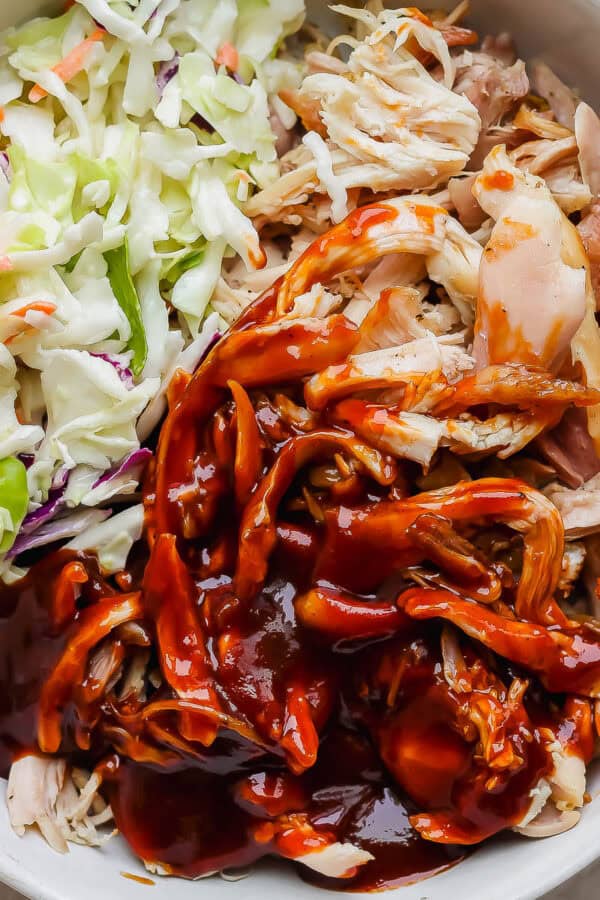 A bowl of smoked pulled chicken with bbq sauce and coleslaw.