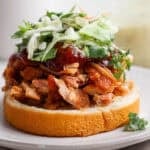 A smoked pulled chicken sandwich on a bun with bbq sauce and slaw.