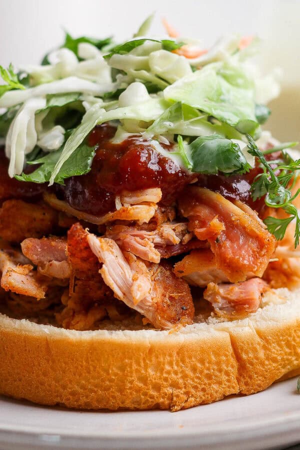 A smoked pulled chicken sandwich on a bun with bbq sauce and slaw.