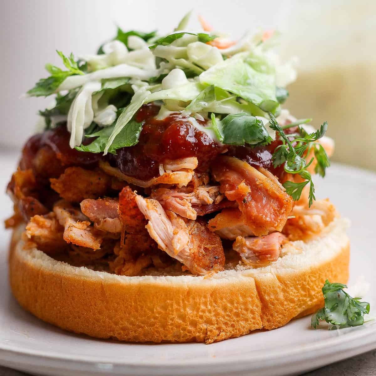 A smoked pulled chicken sandwich on a bun with bbq sauce and slaw.