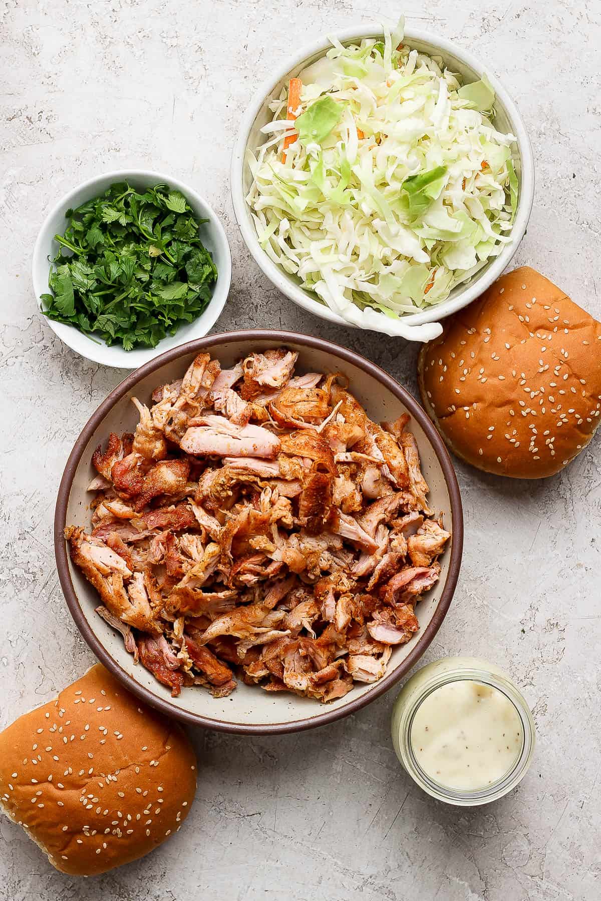 Ingredients for making smoked pulled chicken sandwiches in separate bowls.