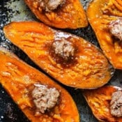 Halved smoked sweet potatoes on a baking sheet with cinnamon sugar butter on top.