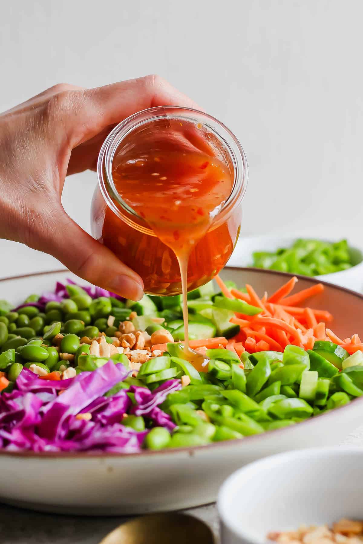 Sweet chili vinaigrette being poured over a chopped pea salad.