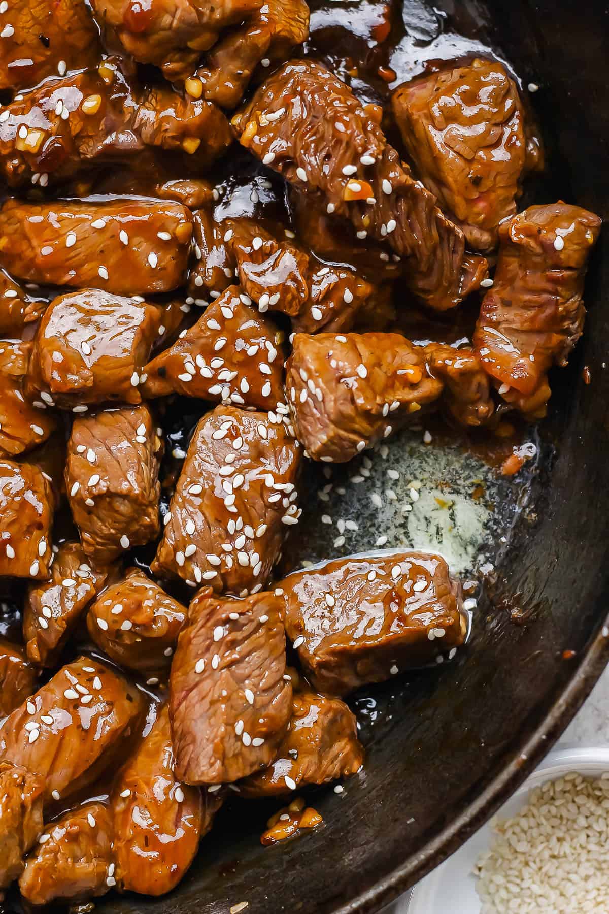 Teriyaki steak bites in a skillet coated in teriyaki sauce.