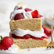 Gluten free strawberry shortcake on a plate topped with whipped cream and strawberries