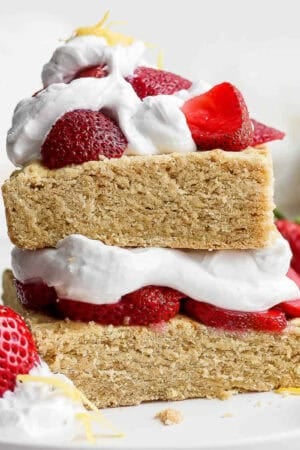 Gluten free strawberry shortcake on a plate topped with whipped cream and strawberries