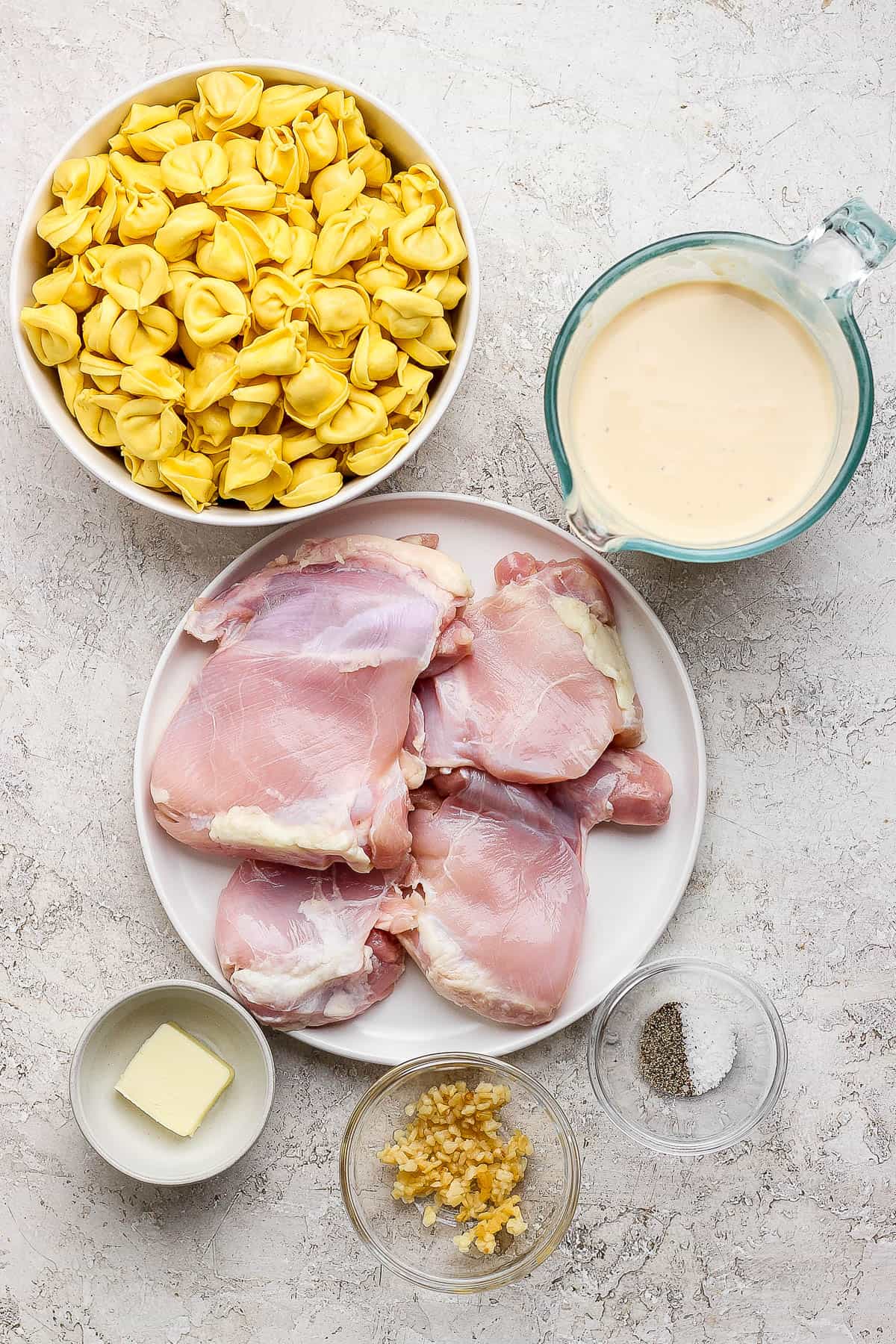 Ingredients for chicken tortellini alfredo in bowls and plates.
