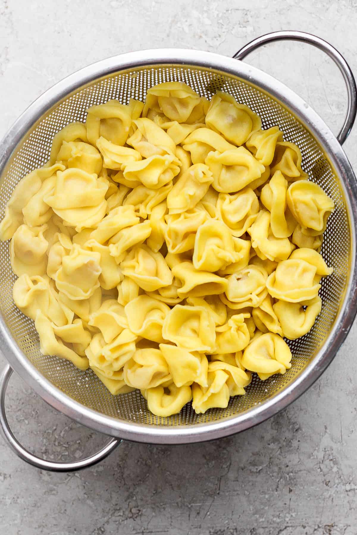 Cooked cheese tortellini in a colander.