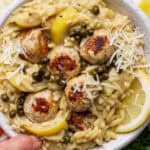 A bowl of chicken piccata meatballs in orzo with capers and parmesan cheese.
