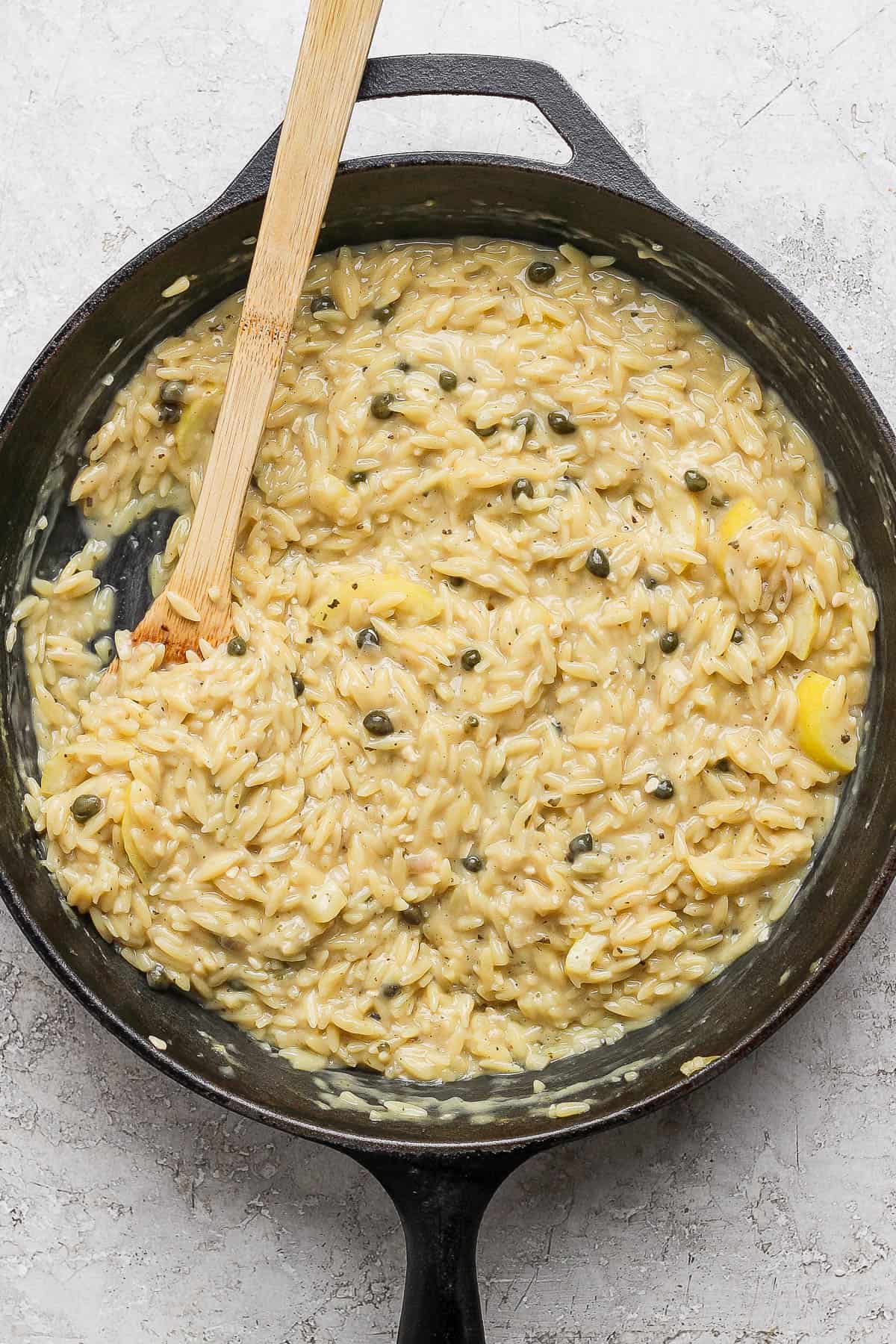 The skillet with the orzo fully cooked in the piccata sauce.