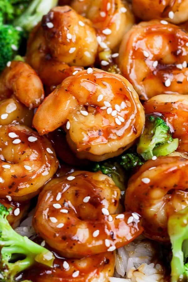 A plate of rice covered with teriyaki shrimp and broccoli.
